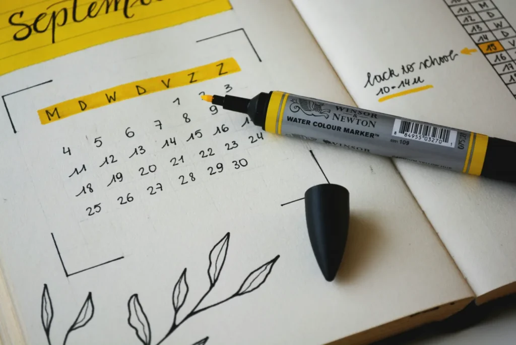 Open bullet journal showing a September calendar with a yellow water-colour marker resting on it
