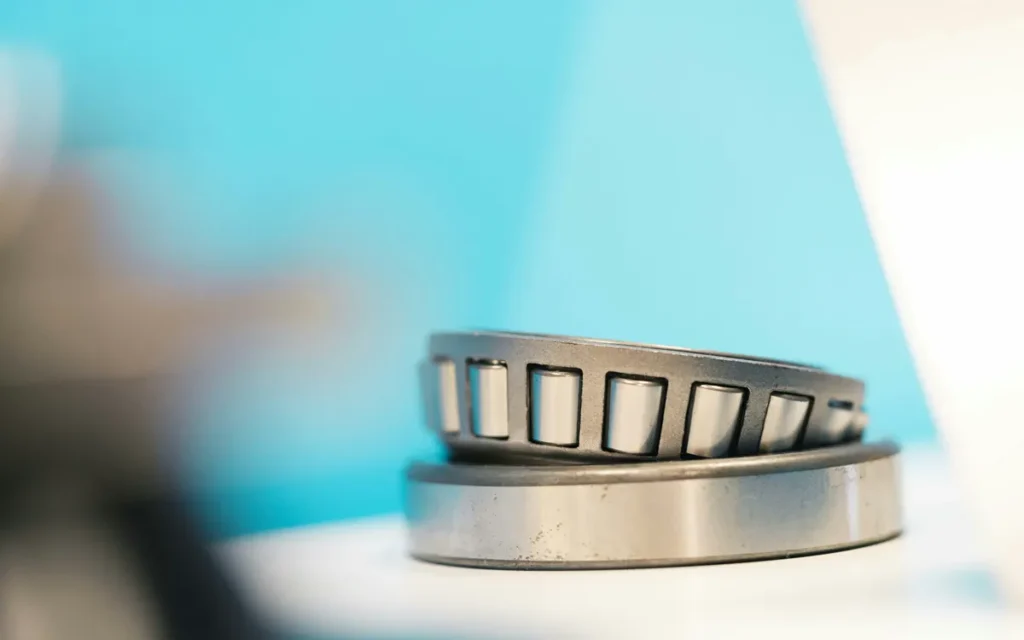 Tapered roller bearing resting on a white surface against a blue backdrop