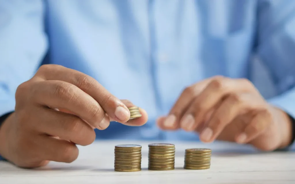 Hands stacking gold coins into short piles on a white table