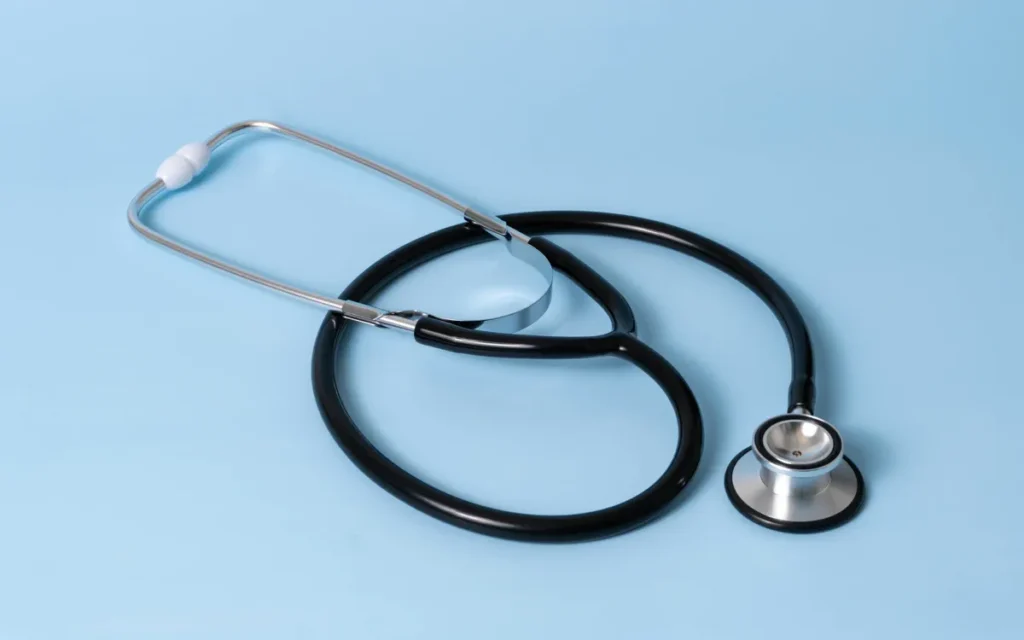 Black stethoscope with a silver chest piece on a pale blue background