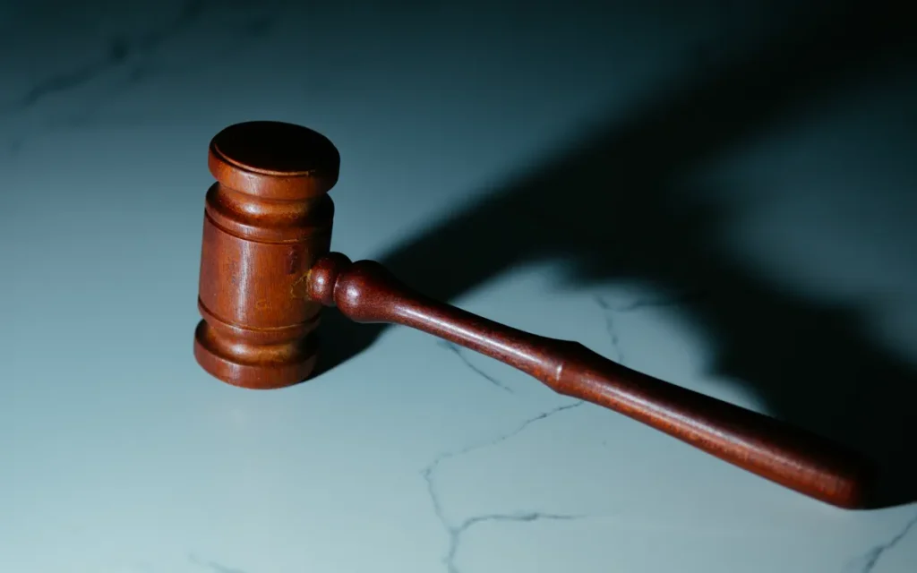 Wooden judge's gavel on pale marble, casting a long shadow